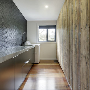 Medium sized contemporary galley utility room in Sydney with a submerged sink, flat-panel cabinets, black cabinets, concrete worktops, black walls and medium hardwood flooring.