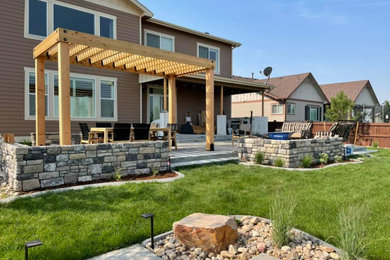 Inspiration for a mid-sized rustic backyard concrete paver patio kitchen remodel in Denver with a pergola