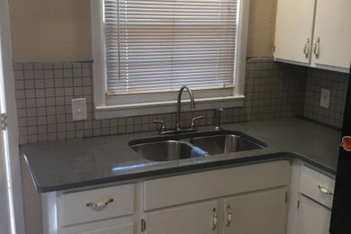 Example of a mid-sized classic l-shaped ceramic tile and beige floor enclosed kitchen design in Austin with flat-panel cabinets, white cabinets, quartz countertops, white backsplash, no island, gray countertops and ceramic backsplash