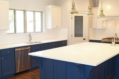 Example of a mid-sized transitional l-shaped medium tone wood floor kitchen design in Little Rock with a double-bowl sink, shaker cabinets, blue cabinets, quartz countertops, white backsplash, subway tile backsplash, stainless steel appliances and an island
