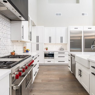 Immagine di una grande cucina classica con lavello stile country, ante bianche, paraspruzzi bianco, elettrodomestici in acciaio inossidabile, parquet chiaro, isola, ante in stile shaker, top in superficie solida e paraspruzzi con piastrelle in ceramica