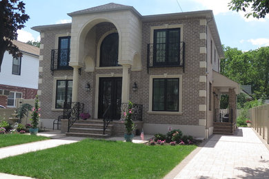 Inspiration for a large timeless beige two-story brick house exterior remodel in New York with a hip roof and a shingle roof