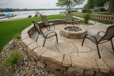 Example of a large transitional backyard stone patio design in Chicago with a fire pit and no cover