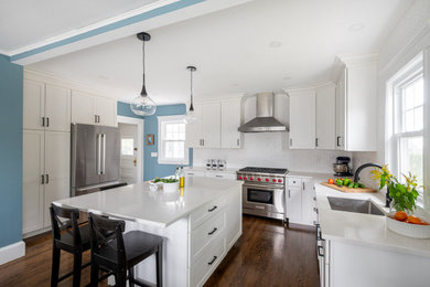 Eat-in kitchen - large transitional u-shaped dark wood floor and brown floor eat-in kitchen idea in Boston with an undermount sink, shaker cabinets, white cabinets, quartz countertops, white backsplash, ceramic backsplash, stainless steel appliances, an island and white countertops