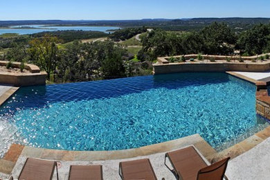 Pool - traditional backyard custom-shaped infinity pool idea in Austin