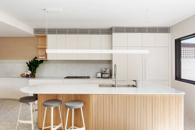 This is an example of a mid-sized contemporary galley eat-in kitchen in Other with a drop-in sink, flat-panel cabinets, white cabinets, white splashback, panelled appliances, terrazzo floors, with island, grey floor and white benchtop.