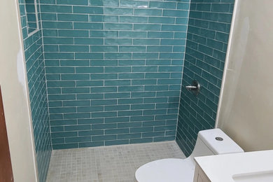 Bathroom - mid-sized tropical 3/4 blue tile and ceramic tile ceramic tile, beige floor and single-sink bathroom idea in Tampa with recessed-panel cabinets, white cabinets, a one-piece toilet, beige walls, an undermount sink, quartz countertops, white countertops, a niche and a freestanding vanity