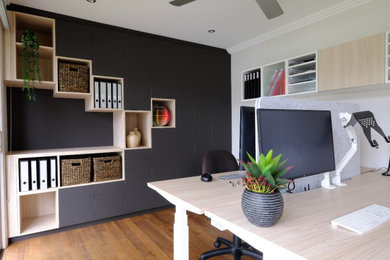 Diseño de estudio minimalista pequeño con paredes blancas, suelo de madera oscura, escritorio empotrado y suelo marrón