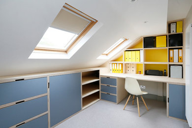 Design ideas for a contemporary home office in London with yellow walls, a built-in desk and grey floor.