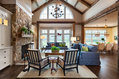 Design ideas for a mid-sized country open concept living room in Other with beige walls, dark hardwood floors, a standard fireplace, a stone fireplace surround and brown floor.