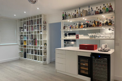 Medium sized contemporary home bar in London with white splashback and white worktops.