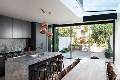 Inspiration for a contemporary single-wall eat-in kitchen in London with a single-bowl sink, dark wood cabinets, grey splashback, marble splashback, medium hardwood floors, with island, brown floor and grey benchtop.