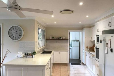 Inspiration for a mid-sized country u-shaped eat-in kitchen in Sydney with a double-bowl sink, shaker cabinets, white cabinets, quartzite benchtops, grey splashback, white appliances, no island and pink floor.