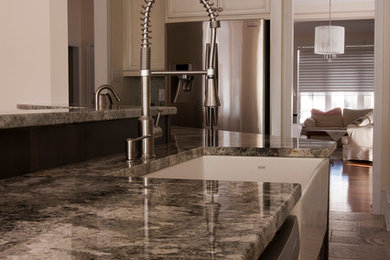 Mid-sized transitional galley travertine floor open concept kitchen photo in Ottawa with a farmhouse sink, raised-panel cabinets, granite countertops, multicolored backsplash, glass tile backsplash, stainless steel appliances and an island