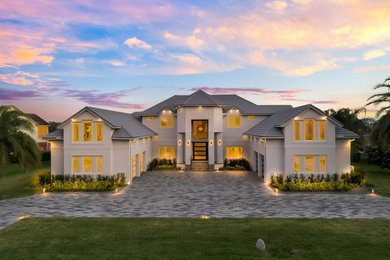 This is an example of a large contemporary two-storey stucco white house exterior in Orlando with a hip roof and a tile roof.