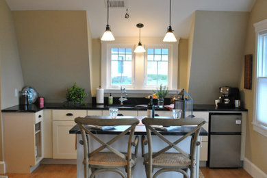 Example of a small transitional single-wall light wood floor and vaulted ceiling eat-in kitchen design in Providence with an undermount sink, shaker cabinets, white cabinets, soapstone countertops, an island and black countertops