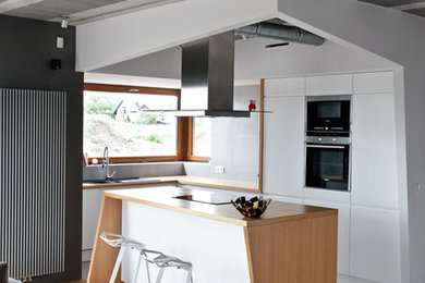 Example of a mid-sized trendy galley light wood floor eat-in kitchen design in Miami with a drop-in sink, flat-panel cabinets, white cabinets, wood countertops, stainless steel appliances and an island