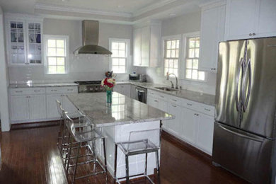 Example of a mid-sized l-shaped dark wood floor eat-in kitchen design in Charlotte with an integrated sink, raised-panel cabinets, white cabinets, granite countertops, white backsplash, subway tile backsplash, stainless steel appliances and an island