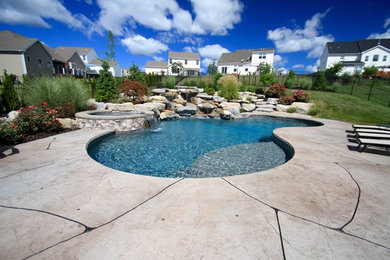 Photo of a large contemporary backyard custom-shaped pool in Philadelphia with a hot tub and stamped concrete.