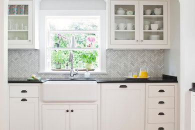 Design ideas for a large traditional kitchen in Seattle with a farmhouse sink, white cabinets, granite benchtops, grey splashback, glass tile splashback, stainless steel appliances, no island, glass-front cabinets and medium hardwood floors.