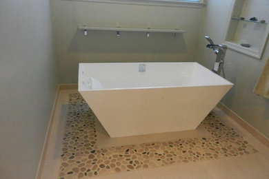 Example of a mid-sized trendy master beige tile and pebble tile porcelain tile bathroom design in Baltimore with flat-panel cabinets, light wood cabinets, a one-piece toilet, green walls, an undermount sink and recycled glass countertops