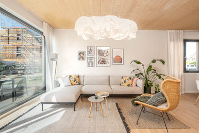 Example of a large danish open concept light wood floor and wood ceiling living room design in Berlin with beige walls and no fireplace