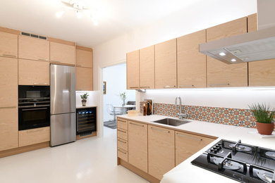 Photo of a modern separate kitchen in Stockholm with flat-panel cabinets, light wood cabinets, stainless steel appliances, painted wood floors, no island, white floor and white benchtop.