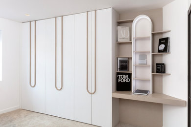 Medium sized modern gender neutral built-in wardrobe in London with raised-panel cabinets and feature lighting.