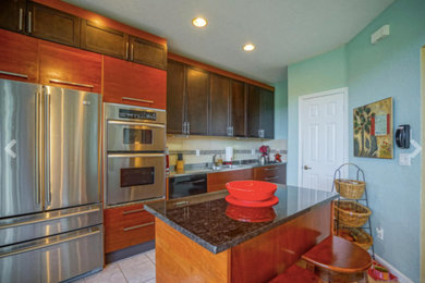 Inspiration for a mid-sized eclectic single-wall ceramic tile and beige floor open concept kitchen remodel in Miami with a double-bowl sink, flat-panel cabinets, dark wood cabinets, terrazzo countertops, beige backsplash, ceramic backsplash, stainless steel appliances and an island