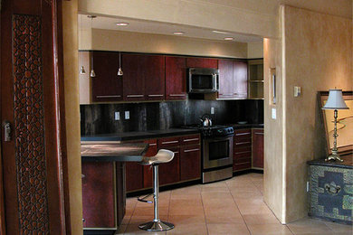 Trendy u-shaped open concept kitchen photo in Albuquerque with an undermount sink, flat-panel cabinets, dark wood cabinets, tile countertops, black backsplash, porcelain backsplash and stainless steel appliances