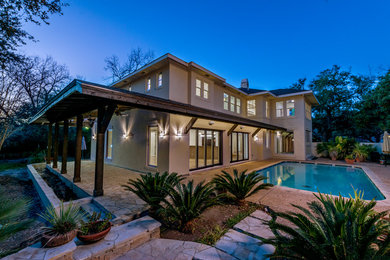 Large transitional beige two-story stucco house exterior photo in Austin with a hip roof and a shingle roof