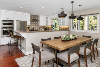 Example of a mid-sized mountain style u-shaped dark wood floor and brown floor eat-in kitchen design in Other with raised-panel cabinets, white cabinets, gray backsplash, porcelain backsplash, stainless steel appliances, a peninsula, gray countertops, an undermount sink and quartz countertops
