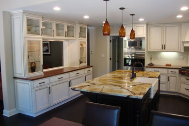 Inspiration for a large transitional u-shaped dark wood floor and brown floor eat-in kitchen remodel in San Francisco with a farmhouse sink, recessed-panel cabinets, white cabinets, marble countertops, white backsplash, subway tile backsplash, black appliances and an island