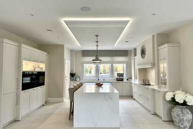 Large traditional open plan kitchen in Other with an integrated sink, white cabinets, white splashback, integrated appliances, porcelain flooring, an island, white floors and white worktops.