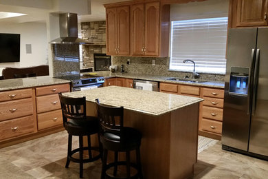 Example of a mid-sized transitional u-shaped dark wood floor enclosed kitchen design in Salt Lake City with an undermount sink, raised-panel cabinets, light wood cabinets, granite countertops, beige backsplash, stainless steel appliances and an island