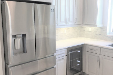 Eat-in kitchen - large coastal u-shaped travertine floor and white floor eat-in kitchen idea in Miami with an undermount sink, raised-panel cabinets, white cabinets, quartzite countertops, multicolored backsplash, porcelain backsplash, stainless steel appliances, two islands and white countertops
