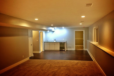 Basement - large contemporary look-out laminate floor basement idea in Grand Rapids with gray walls