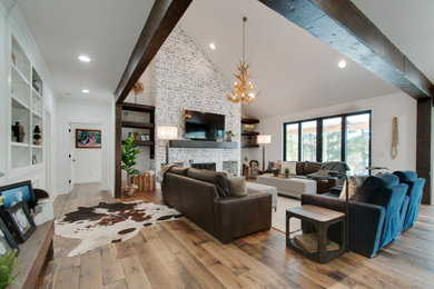 Mid-sized cottage open concept medium tone wood floor, brown floor, vaulted ceiling and exposed beam living room photo in Nashville with white walls, a standard fireplace, a brick fireplace and a wall-mounted tv