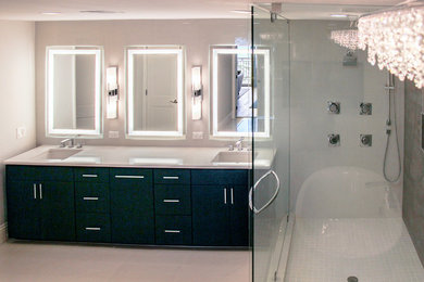 Photo of a large modern master bathroom in Tampa with flat-panel cabinets, black cabinets, engineered quartz benchtops, a freestanding tub, a corner shower, white tile, porcelain tile, white walls, porcelain floors, an undermount sink, white floor and a hinged shower door.