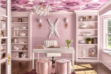 Пример оригинального дизайна: домашняя библиотека среднего размера в классическом стиле с розовыми стенами, темным паркетным полом и отдельно стоящим рабочим столом