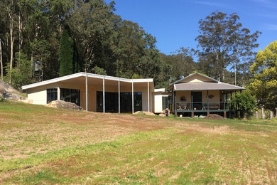 This is an example of a large contemporary one-storey beige exterior in Melbourne with mixed siding and a flat roof.