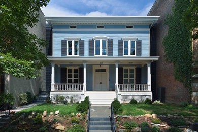Blue townhouse exterior in New York with wood siding, a hip roof and clapboard siding.