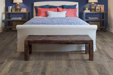 Example of a mid-sized trendy master laminate floor, brown floor and vaulted ceiling bedroom design in Montreal with blue walls and no fireplace