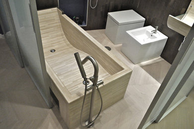 Design ideas for a medium sized contemporary ensuite bathroom in Rome with beige cabinets, a japanese bath, a two-piece toilet, brown tiles, stone tiles, multi-coloured walls, light hardwood flooring, a wall-mounted sink and brown floors.