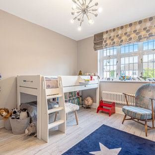 Example of a mid-sized eclectic gender-neutral laminate floor and gray floor nursery design in London with gray walls