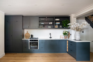 Ejemplo de cocinas en L actual abierta con armarios estilo shaker, puertas de armario azules, encimera de cuarcita y encimeras blancas
