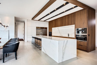 This is an example of a contemporary eat-in kitchen in Calgary with an undermount sink, flat-panel cabinets, dark wood cabinets, white splashback, stone slab splashback, stainless steel appliances, with island and beige floor.
