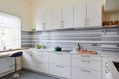 Small contemporary l-shaped kitchen/diner in London with a built-in sink, flat-panel cabinets, beige cabinets, quartz worktops, grey splashback, marble splashback, stainless steel appliances, lino flooring, a breakfast bar, grey floors, grey worktops, a vaulted ceiling and a feature wall.