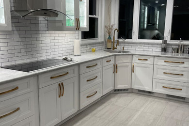 Bild på ett stort funkis grå grått kök, med en enkel diskho, luckor med infälld panel, vita skåp, granitbänkskiva, vitt stänkskydd, stänkskydd i porslinskakel, rostfria vitvaror, vinylgolv och grått golv