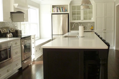 Inspiration for a mid-sized timeless l-shaped dark wood floor and brown floor enclosed kitchen remodel in Philadelphia with an undermount sink, recessed-panel cabinets, white cabinets, solid surface countertops, multicolored backsplash, mosaic tile backsplash, stainless steel appliances, an island and white countertops
